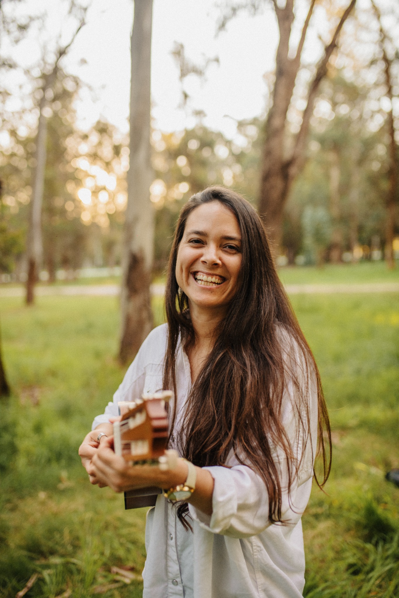 Luna Córdoba sonriendo con una guitarra en la naturaleza